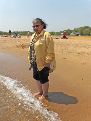 2 photos show Nanta standing in the water with her pants rolled up to her knees.  The water is making little waves, and is covering her ankles.